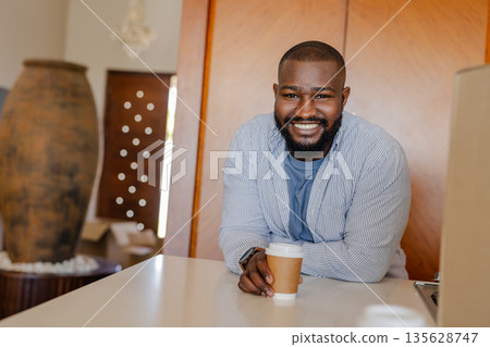 Smiling man enjoying coffee at home, leaning on kitchen counter 135628747