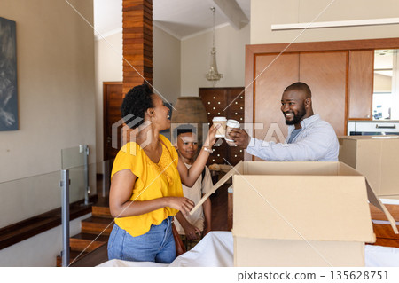 Family unpacking boxes at home, enjoying coffee break and smiling together Family unpacking boxes at home, enjoying coffee break and smiling together 135628751