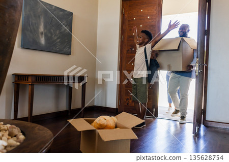 Father and son entering new home, carrying boxes and smiling with excitement 135628754