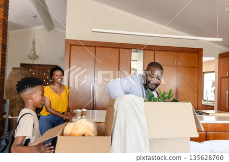 Family unpacking boxes in new home, smiling and enjoying moving process 135628760