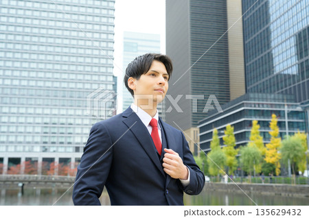 辦公區路邊綠樹成蔭,一位穿著西裝的男士正在等候。 辦公區路邊綠樹成蔭,一位穿著西裝的男士正在等候。 135629432