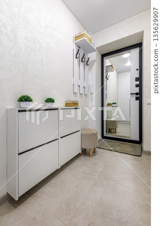 Bright minimalist entryway interior with white shoe cabinet and mirror 135629907