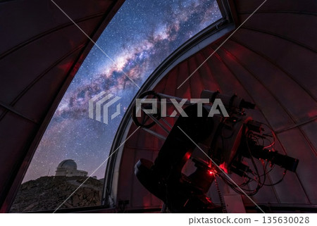 Telescope inside observatory dome with view of Milky Way galaxy and observatory building outside 135630028