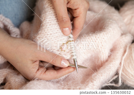 Soft wool knitting process in female hands creating warm textile in peaceful home atmosphere Soft wool knitting process in female hands creating warm textile in peaceful home atmosphere 135630032