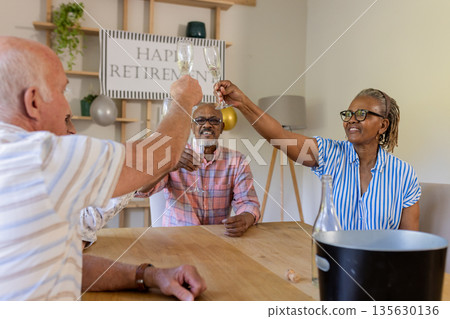 Senior friends celebrating retirement with champagne toast at home, smiling joyfully Senior friends celebrating retirement with champagne toast at home, smiling joyfully 135630136