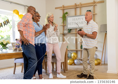 Celebrating retirement at home, senior friends clapping and smiling joyfully together 135630146
