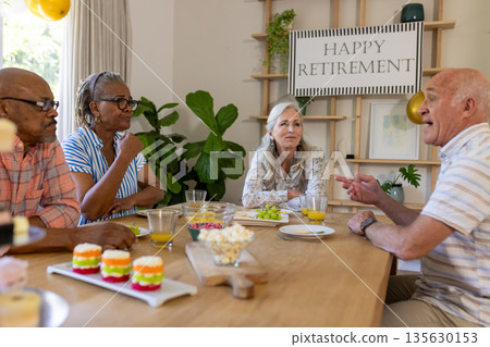 Senior friends enjoying retirement party, sharing stories and laughter at home 135630153