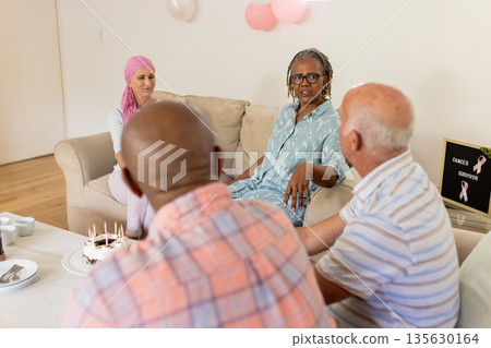 Senior friends celebrating cancer survivor with cake and conversation in living room Senior friends celebrating cancer survivor with cake and conversation in living room 135630164