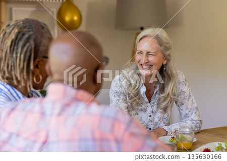 Senior friends enjoying conversation and laughter over lunch at home Senior friends enjoying conversation and laughter over lunch at home 135630166