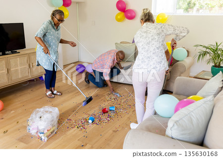 Senior friends cleaning up colorful confetti after fun indoor celebration Senior friends cleaning up colorful confetti after fun indoor celebration 135630168