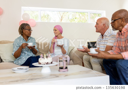 Senior friends enjoying coffee and cake while chatting in cozy living room 135630198