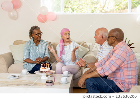 Celebrating birthday, senior friends with cake and coffee, having lively conversation 135630200