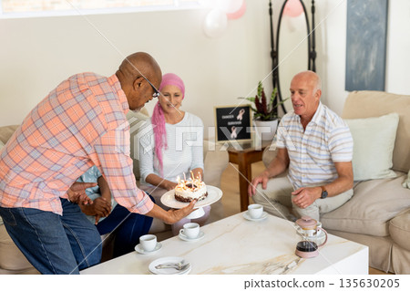 Celebrating birthday, senior friends having cake and coffee in cozy living room Celebrating birthday, senior friends having cake and coffee in cozy living room 135630205