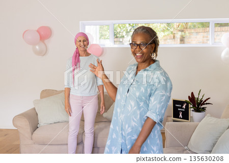 Celebrating cancer remission, senior women with balloons and joyful expressions at home 135630208