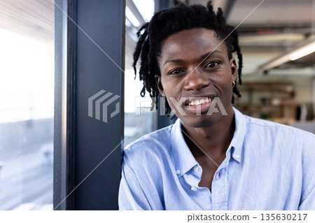 African American man in casual shirt smiling confidently in modern office setting 135630217