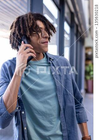 Young man in office talking on smartphone, looking confident and engaged 135630218