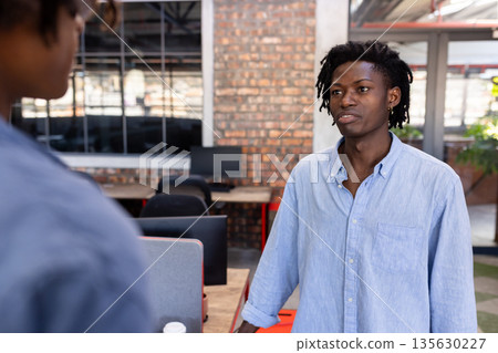 Discussing project, African American man in casual shirt with colleague in modern office Discussing project, African American man in casual shirt with colleague in modern office 135630227