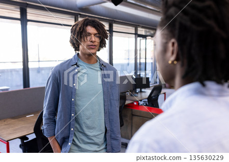Two colleagues discussing project in modern office, fostering creative collaboration 135630229