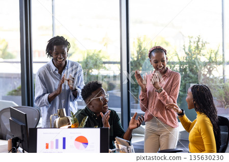 Celebrating success, African American colleagues smiling and clapping in modern office 135630230