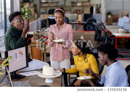 In office, African American colleagues having cake, smiling and socializing during break 135630236