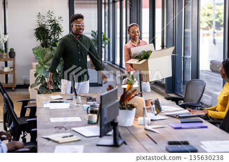 African American colleagues welcoming new team member with box at modern office African American colleagues welcoming new team member with box at modern office 135630238