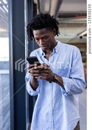 Young man in office using smartphone, concentrating on work tasks 135630239