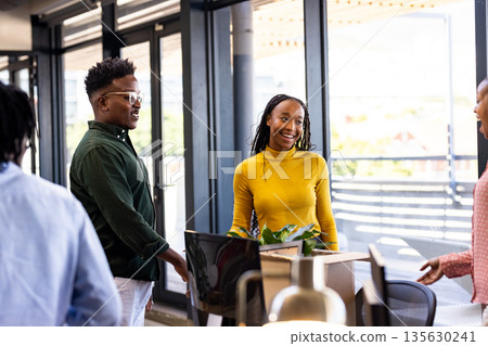Colleagues in modern office smiling and discussing project near large windows 135630241
