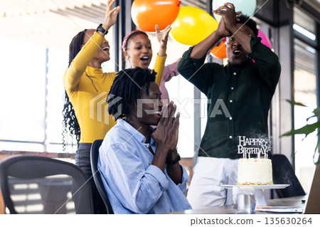 Celebrating birthday in office, colleagues clapping with cake and colorful balloons 135630264