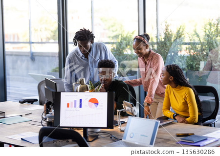 Collaborating on project, African American team using laptops and charts in office Collaborating on project, African American team using laptops and charts in office 135630286