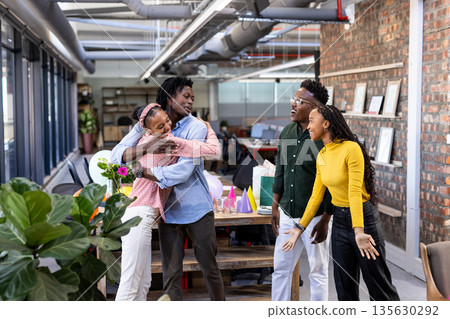 Celebrating in modern office, African American colleagues embracing and smiling joyfully 135630292
