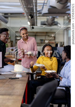 Sharing cake and conversation, colleagues celebrating in office with joyful moments 135630321