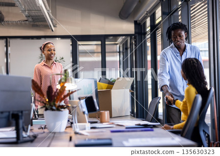 Greeting each other in modern office, African American colleagues smiling and collaborating Greeting each other in modern office, African American colleagues smiling and collaborating 135630323