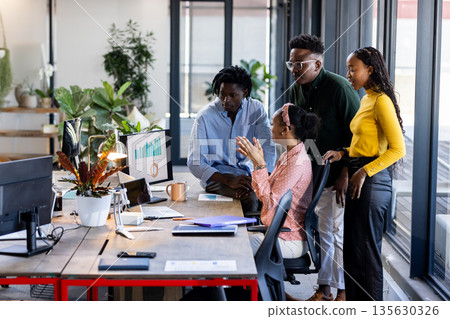 In office, team discussing data on computer screen, collaborating enthusiastically In office, team discussing data on computer screen, collaborating enthusiastically 135630326
