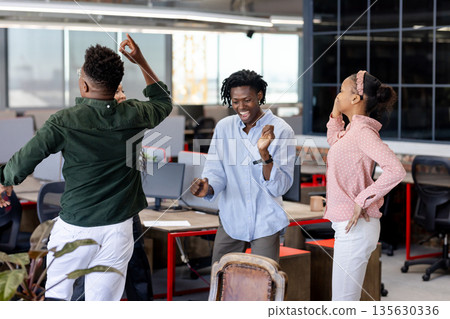 In office, colleagues celebrating successful project, dancing joyfully together 135630336