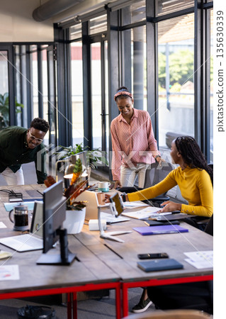 Collaborating in modern office, diverse team discussing project around table 135630339