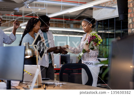 Celebrating promotion with flowers and handshake, African American colleagues in office 135630382