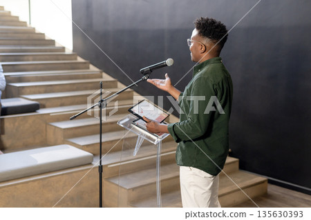 African American man presenting with tablet at modern office, engaging audience African American man presenting with tablet at modern office, engaging audience 135630393