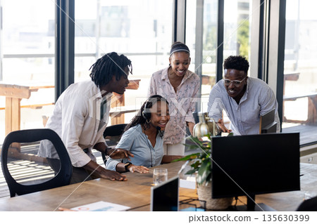 Collaborating in office, team enthusiastically working together around computer Collaborating in office, team enthusiastically working together around computer 135630399