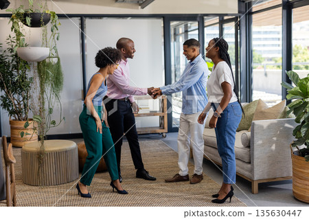 Colleagues greeting each other with handshake in modern office lounge area Colleagues greeting each other with handshake in modern office lounge area 135630447