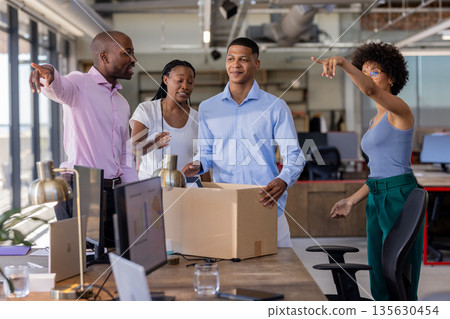 Colleagues unpacking box in modern office, discussing new project enthusiastically 135630454