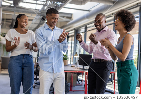 Business team clapping and smiling in modern office, celebrating success together 135630457