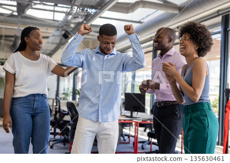 Colleagues celebrating success in modern office, smiling and clapping with joy 135630461
