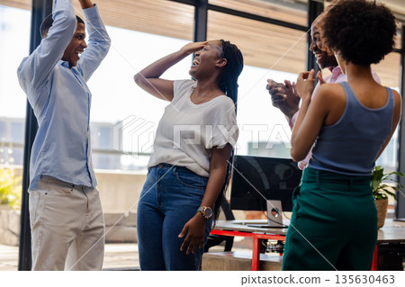 Colleagues celebrating success in office, smiling and clapping with excitement Colleagues celebrating success in office, smiling and clapping with excitement 135630463