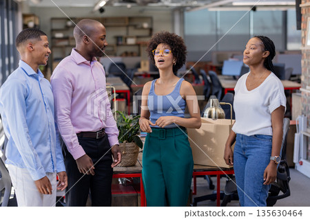 Colleagues in office discussing project, smiling and engaging in conversation 135630464
