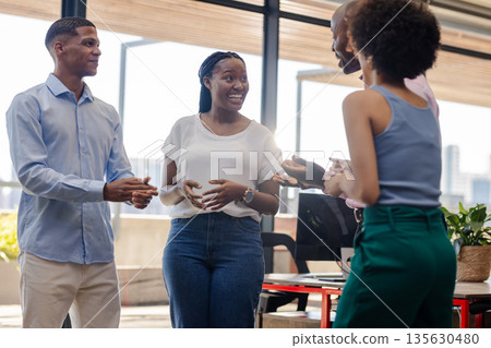 Colleagues in office discussing project, smiling and engaging in lively conversation Colleagues in office discussing project, smiling and engaging in lively conversation 135630480