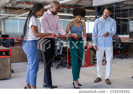 Colleagues cutting ribbon in modern office, celebrating new business opening 135630482