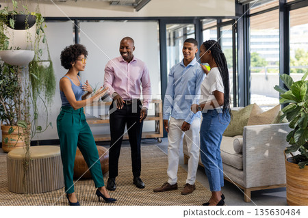 Colleagues in office discussing project, smiling and engaging in lively conversation 135630484