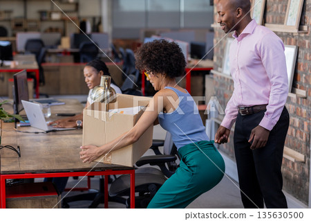 Moving office supplies, African American colleagues collaborating efficiently in modern workspace 135630500