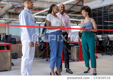 African American colleagues cutting ribbon in modern office, celebrating new opening 135630510