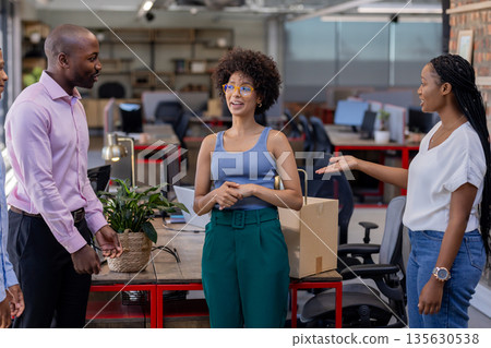 Colleagues in office discussing project, smiling and engaging in lively conversation 135630538